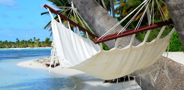 White hammock between palm trees on a serene beach