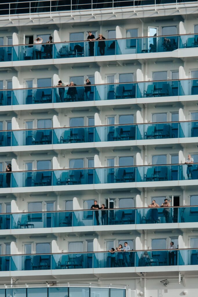 Cruise ship with multiple balcony cabins showing different cruise cabin types with passengers enjoying the view.